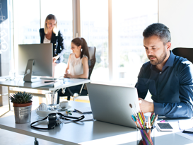 Profond Anlagestiftung Logo Drei Geschäftsleute, die in einem hellen Büro am Laptop arbeiten.