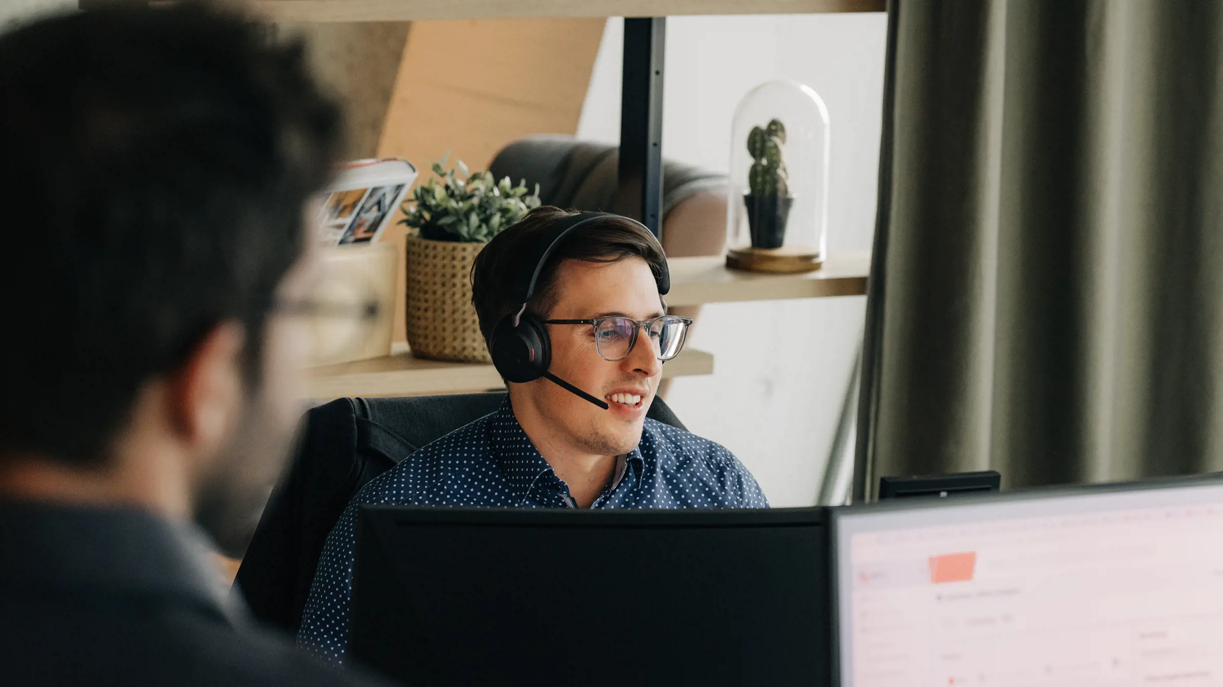 Man sitting in front of a computer with headset