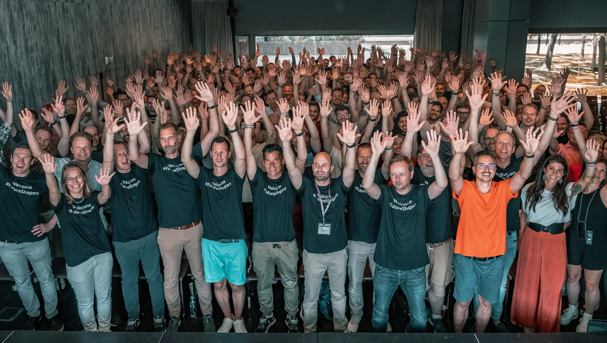 Viele Menschen mit gleichem T-Shirt heben alle die Hände in die Luft